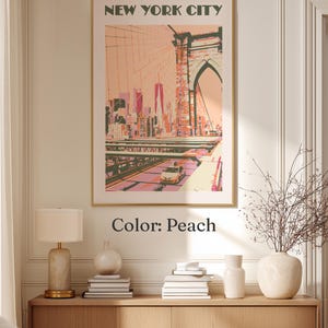 May include: A framed wall art print titled NEW YORK CITY featuring a stylized illustration of the Brooklyn Bridge and city skyline in shades of peach, pink, and dark green. A yellow taxi is visible on the bridge deck below the bridge arch.