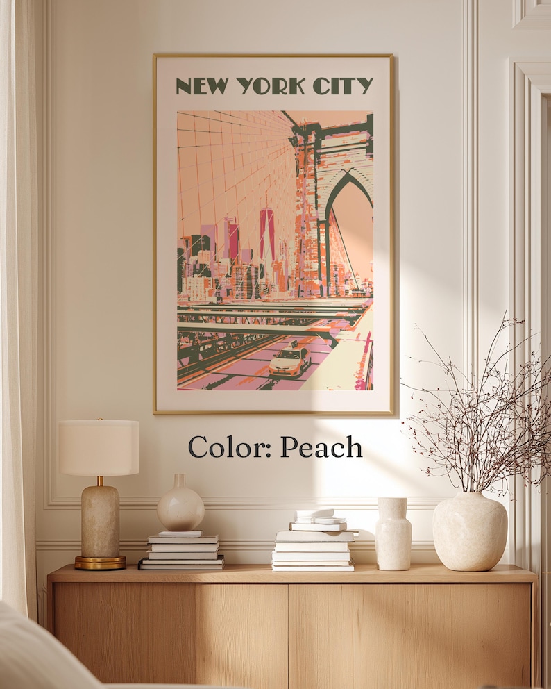 May include: A framed wall art print titled NEW YORK CITY featuring a stylized illustration of the Brooklyn Bridge and city skyline in shades of peach, pink, and dark green. A yellow taxi is visible on the bridge deck below the bridge arch.