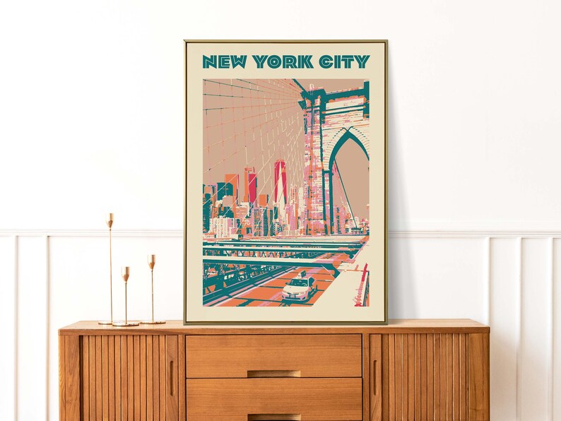 May include: A vintage-style poster with the text "NEW YORK CITY" in teal and white. The poster features a colorful illustration of the Brooklyn Bridge with a yellow taxi cab driving across it.