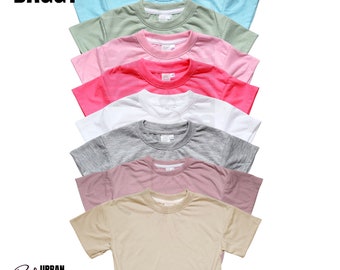 May include: A stack of eight plain, short-sleeved t-shirts in various colors, including light blue, green, pink, red, white, gray, mauve, and beige. The shirts are arranged from top to bottom in order of color. The text "BAGGY" is at the top of the image. The text "URBAN BLOSSOM BLANKS, LLC" is at the bottom of the image.