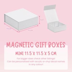 May include: Two white magnetic gift boxes, one closed and one open, with dimensions of 11.5 cm by 11.5 cm by 5 cm. The text reads: MAGNETIC GIFT BOXES, MINI 11.5 X 11.5 X 5 CM, For bigger sizes check other listings! Can be personalised with acrylic or vinyl decal names in any colour!