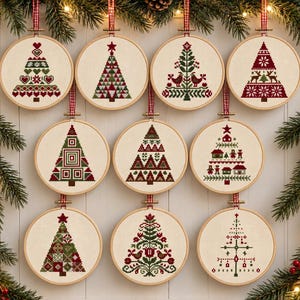 May include: Nine circular wooden embroidery hoops containing cross-stitch fabric with various Christmas tree designs in red, green, and white. Each hoop features a red and white checkered ribbon hanger for display against a white paneled wall.