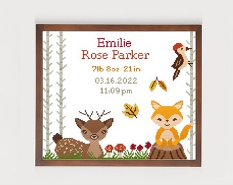 May include: A framed cross-stitch design featuring a woodland scene with a deer, fox, and woodpecker. The design includes the name "Emilie Rose Parker", birth date "03.16.2022", and birth stats "7lb 8oz 21in 11:09pm".