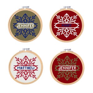 May include: Four round embroidery hoops with snowflake designs and personalized names. The hoops are in red, white, and green colors. The names are "Jennifer", "Mary", "Matthew", and "Jennifer".