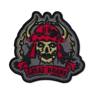 May include: Embroidered patch with a skull design, featuring a red headdress and banner. The skull has gold and black detailing, with a chain and horns. The banner reads "GREAT KHANS" in red. The patch has a grey background and a black border.