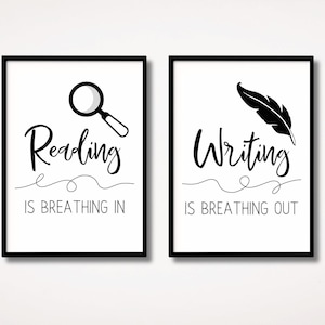May include: Two framed wall art prints with black frames and white backgrounds. The left print features a magnifying glass icon, the text Reading IS BREATHING IN, and a line. The right print features a feather quill, the text Writing IS BREATHING OUT, and a line.
