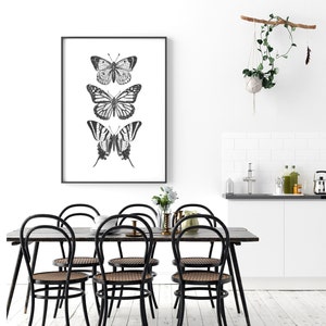 May include: Black and white framed print of three butterflies with a white background. The butterflies are arranged vertically, with the largest butterfly at the top and the smallest butterfly at the bottom.