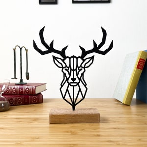 May include: Black geometric deer head sculpture on a wooden base. The deer head is made of metal and has a modern, minimalist design.