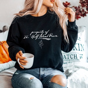 May include: Black sweatshirt with white text that reads "property of The Half Blood Prince" with a snake graphic below the text.