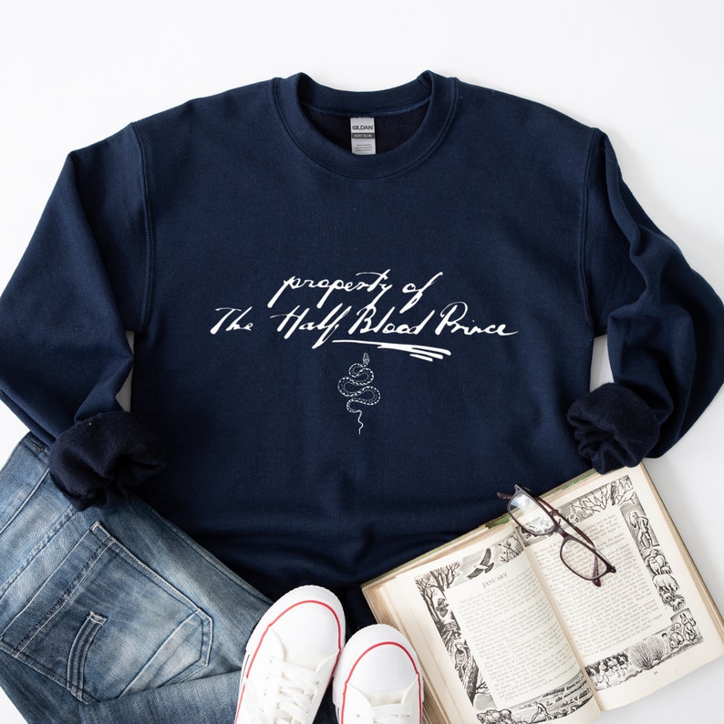 May include: Navy blue sweatshirt with white text that reads "property of The Half Blood Prince" with a snake illustration below the text.