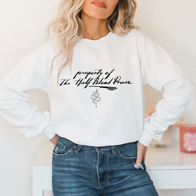 May include: White sweatshirt with the text "property of The Half-Blood Prince" in black cursive writing and a snake graphic.