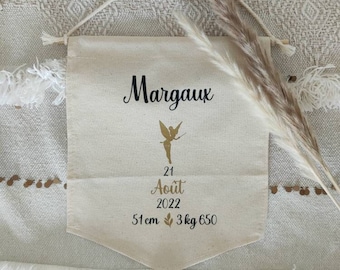 May include: A white canvas banner with the name Margaux printed in black. A gold fairy silhouette is above the text "21 August 2022". Below the date is the text "51 cm 3 kg 650".