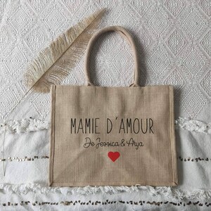 May include: A brown burlap tote bag with black text that reads "Mamie d'Amour De Jessica & Arya" with a red heart.