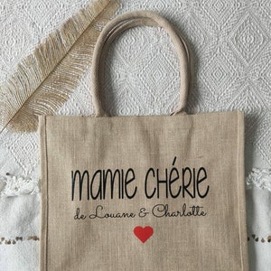 May include: A beige jute tote bag with black text that reads "mamie ch&eacute;rie de Louane & Charlotte" and a red heart.