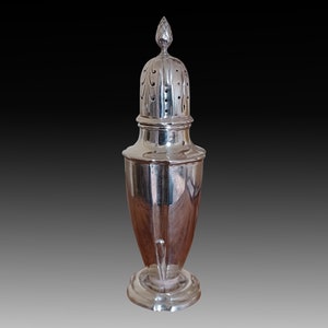 May include: A silver sugar dispenser with a pierced lid and a fluted base.