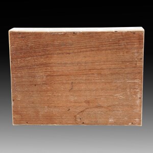 May include: A rectangular wooden box with a natural wood grain finish. The box has a light-colored border and small nails along the edges. The wood has a warm, reddish-brown hue, and the grain is visible.