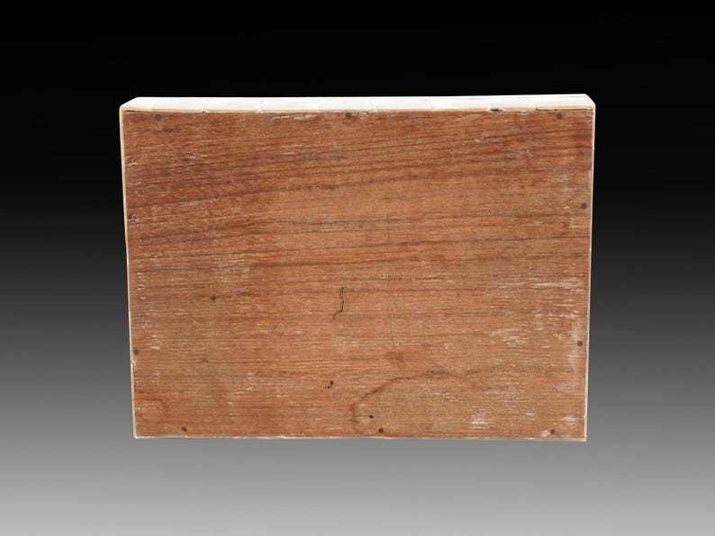 May include: A rectangular wooden box with a natural wood grain finish. The box has a light-colored border and small nails along the edges. The wood has a warm, reddish-brown hue, and the grain is visible.