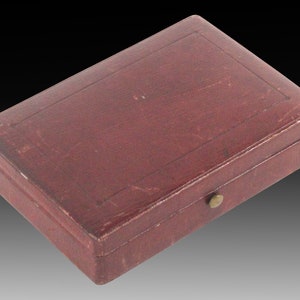 May include: A small, rectangular, burgundy leather box with a brass latch.