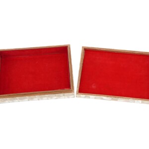 May include: An open rectangular box with a red interior and a mother-of-pearl exterior. The box has a wooden frame and is divided into two halves, showcasing the interior lining.