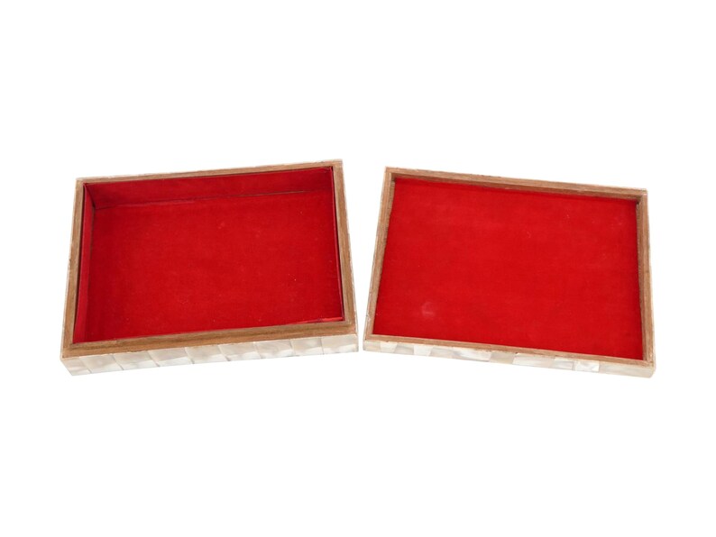 May include: An open rectangular box with a red interior and a mother-of-pearl exterior. The box has a wooden frame and is divided into two halves, showcasing the interior lining.