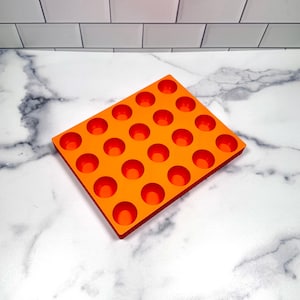 May include: Orange silicone mold with 24 round cavities for making small treats or candies.
