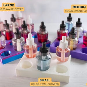 May include: Three different sizes of wallflower holders, labeled "Large", "Medium", and "Small". The holders are made of white plastic and have purple, blue, and white accents. The holders are filled with wallflower bottles, which are clear glass bottles with black caps and colorful liquids inside. The text on the holders reads "Holds 20 Wallflowers", "Holds 12 Wallflowers", and "Holds 6 Wallflowers".