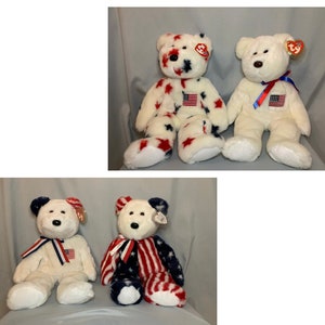 May include: Three plush teddy bears with red, white, and blue patriotic designs. The bears are wearing red, white, and blue ribbons around their necks. The bears are sitting on a light blue surface.