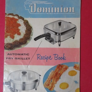 May include: Vintage Dominion Automatic Fry-Skillet Recipe Book. The cover features images of cooked food, including spaghetti, a skillet, eggs, and bacon. The Dominion logo is at the top, with a blue and yellow color scheme.