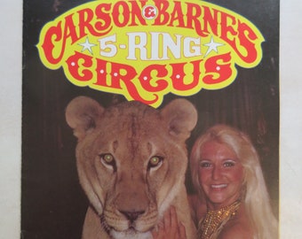 Könnte beinhalten: Ein Vintage-Programm und Souvenirmagazin des Carson & Barnes 5-Ring Circus mit einer Frau und einem Löwen. Das Cover zeigt ein gelbes und rotes Logo mit dem Text "Carson & Barnes 5-Ring Circus".