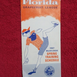 May include: Vintage Florida Grapefruit League baseball schedule from 1967. The cover features a cartoon baseball player in a baseball cap and sunglasses. The schedule includes the Major League Spring Training Schedule.