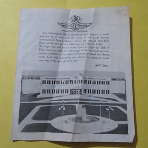 Puede incluir: Un documento antiguo del Indianapolis Motor Speedway, con texto y una ilustración en blanco y negro de un edificio con una fuente. El documento está sobre un fondo amarillo.