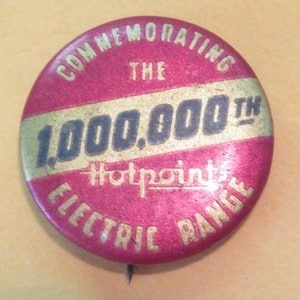 May include: A red and gold button commemorating the 1,000,000th Hotpoint Electric Range. The button has a gold stripe across the middle with the text "1,000,000th" in black letters.