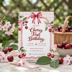 Op de afbeelding: Een uitnodiging voor een verjaardag met een kersenthema. De kaart heeft een roze strik, kersenillustraties en de tekst "Cherry First Birthday". Kersen, bloemen en een mand met kersen omringen de kaart.