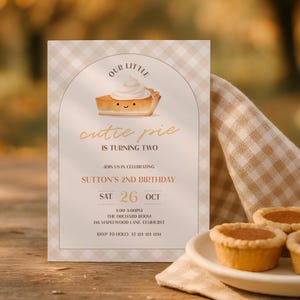 May include: A rectangular birthday invitation card with a beige and white gingham border. The centre features an arched design with a cartoon pie slice, the text 'OUR LITTLE cutie pie IS TURNING TWO', and event details for Sutton's 2nd birthday.