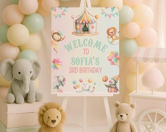 May include: A rectangular sign on a white easel featuring a circus theme with a tent, balloons, and animals. The text reads Welcome to Sofia's 3rd Birthday. The sign is surrounded by pastel balloons, a plush elephant, a lion, and a teddy bear.