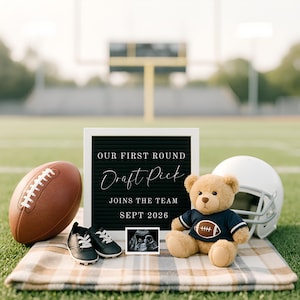 May include: An announcement with a football theme. Includes a brown football, baby shoes, a teddy bear in a football jersey, a white helmet, and a sign reading "OUR FIRST ROUND DRAFT PICK JOINS THE TEAM SEPT 2026". The announcement is set on a football field.