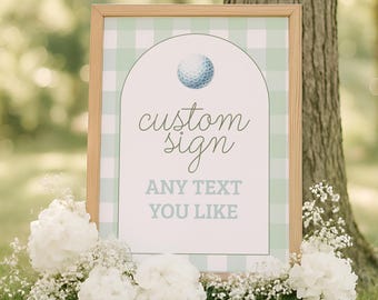 Puede incluir: Un letrero rectangular en un marco de madera clara con un fondo de cuadros vichy en verde claro y blanco. El letrero presenta un diseño arqueado con una ilustración de una pelota de golf, el texto "custom sign" en cursiva y "ANY TEXT YOU LIKE" en letras de molde.