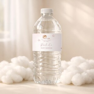 May include: Clear plastic water bottle with a white cap and a label that reads "Rachel's BABY SHOWER." The label features a baby sleeping on a cloud with stars in a soft, neutral color palette. The bottle is surrounded by fluffy white clouds.
