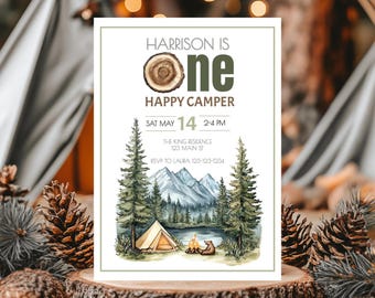 May include: A rectangular birthday invitation card featuring the text Harrison is one happy camper. The design includes a tree ring graphic, a watercolor illustration of a mountain landscape, a tent, a campfire, and a bear in a forest.