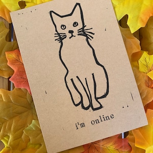 Pu&ograve; includere: Un biglietto marrone con un disegno a linea nera di un gatto seduto con il testo "i'm online" sotto.