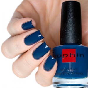 May include: A bottle of Sophiin nail polish in a deep blue color. The bottle is clear and shows the polish inside. A hand is shown with four fingernails painted with the same blue polish.