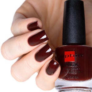 Puede incluir: Una botella de esmalte de uñas de color rojo oscuro de la marca "CND Shellac" con el texto "Nail Polish & Color 2 in 1" en la etiqueta.