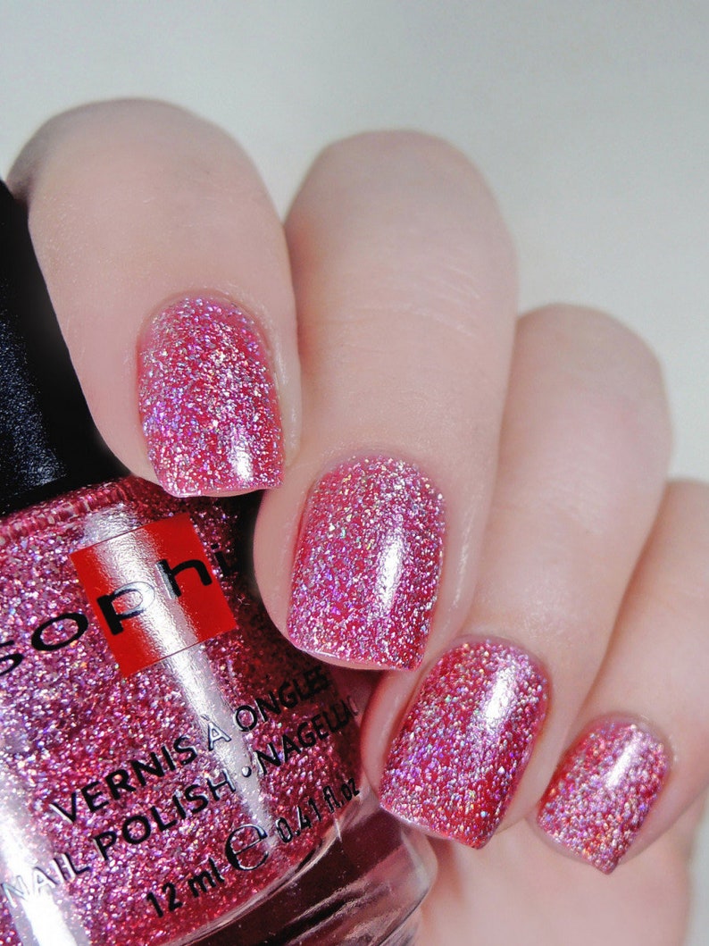 K&ouml;nnte beinhalten: Eine Flasche pinkfarbener Glitzer-Nagellack mit dem Markennamen "Soph" und dem Text "Vernis a Ongle Nail Polish - Nagellack 12 ml e 0.41 fl oz" auf dem Etikett.
