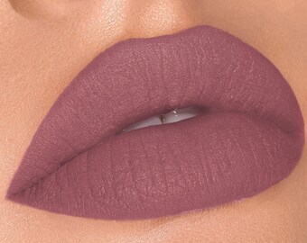 Puede incluir: Primer plano de los labios de una persona con un labial de color malva. El labial tiene un acabado mate y está aplicado de forma uniforme.
