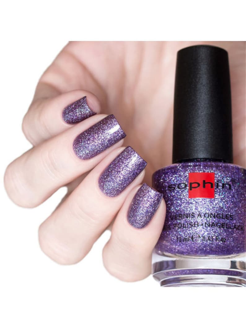 May include: A bottle of purple nail polish with a silver glitter finish. The bottle is labeled "Sophin" and "Vernis a Ongles Nail Polish Nagellack".