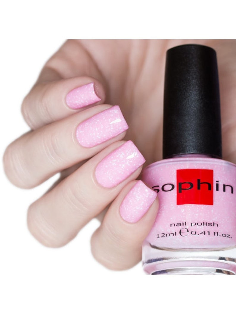 May include: Pink nail polish with a sparkly finish in a clear bottle with a black cap. The bottle label reads "Sophin nail polish 12ml e 0.41 fl.oz."