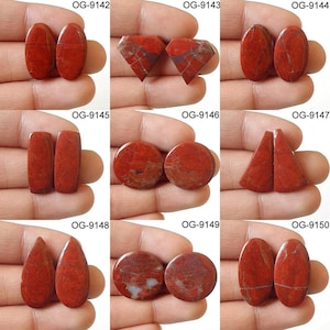 May include: Ten pairs of red jasper cabochons in various shapes, including oval, round, teardrop, and diamond. Each pair is labeled with a unique code, such as OG-9142, OG-9143, and so on.