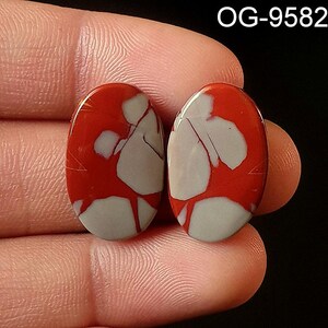 May include: Two oval-shaped red and white jasper cabochons with a marbled pattern. The cabochons are approximately 1 inch in length and 1/2 inch in width.  OG-9582