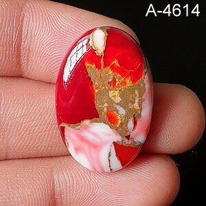 May include: Oval-shaped gemstone with a vibrant red base, accented by gold and white veining. The polished surface reflects light, showcasing the intricate patterns within the stone. The text "A-4614" is visible in the upper right corner.