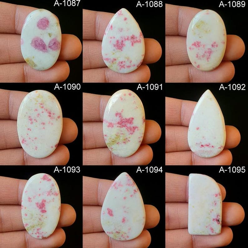 May include: Nine cabochon gemstones with a white base and pink and red inclusions. The gemstones are oval, teardrop, and rectangular shapes. The gemstones are labeled with the numbers A-1087 through A-1095.